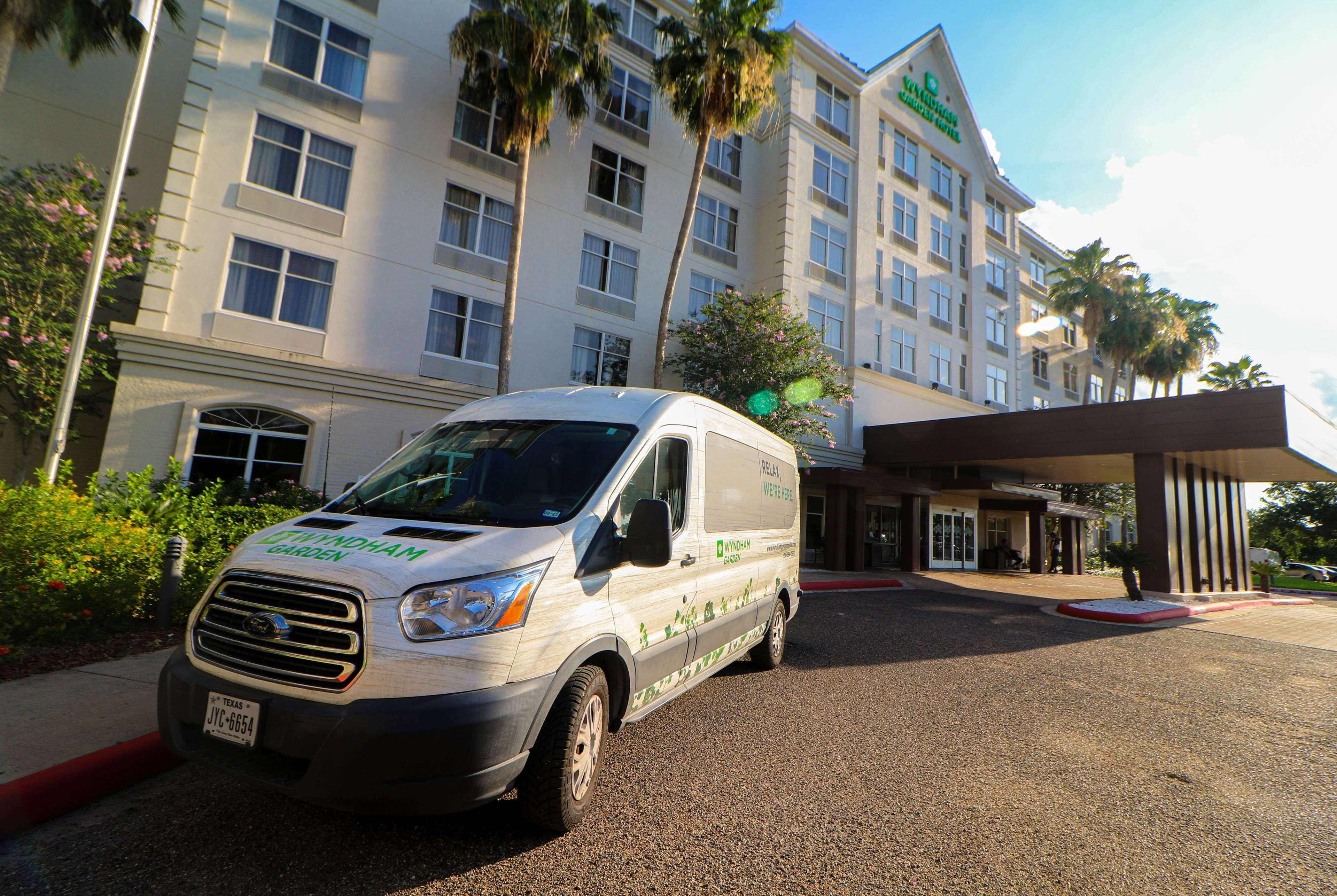 A van parked in front of a hotel with a garden sign, indicating a possible garden or outdoor area.