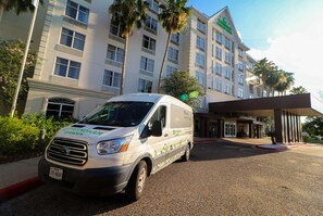 A van parked in front of a hotel with a garden sign, indicating a possible garden or outdoor area.
