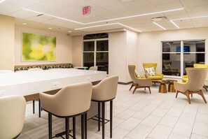 A modern conference room with a long table, bar stools, and yellow chairs.