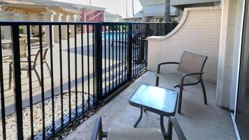 An outdoor seating area with a pool in the background, enclosed by a black metal fence.