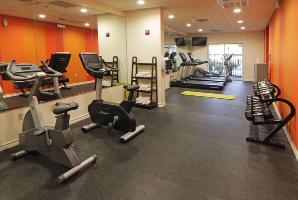 Et fitnesscenter med løbebånd, crosstrainere og vægtbænke.