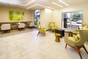 A modern waiting area with a sofa, chairs, and a large window offering a view of the street.