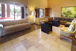 Eine geräumige Lobby mit einem beigen Sofa, einem Couchtisch und einer gemusterten Bank.