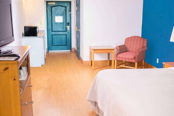 A hotel room with a bed, a TV, a small table, a chair, and a door. - Wyndham Garden Mcallen at La Plaza Mall (McAllen)
