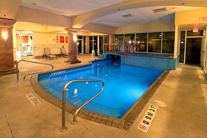 En indendørs swimmingpool med flisekant, et forbud mod dykning-skilt og et tydeligt udgangsskilt.