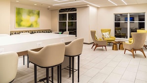A modern conference room with a long table, bar stools, and yellow chairs. - Wyndham Garden Mcallen at La Plaza Mall (McAllen)