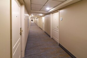 A long, narrow hotel corridor with carpeted floors and doors on both sides. - Wyndham Garden Mcallen at La Plaza Mall (McAllen)
