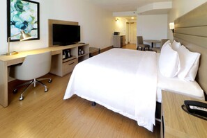 Una habitación de hotel con cama, escritorio, silla, televisor y una pequeña mesa.