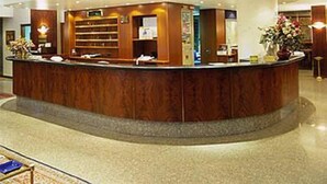 A reception area with a curved counter, a reception desk, and a large plant. - Hotel Crivi's (Milan)