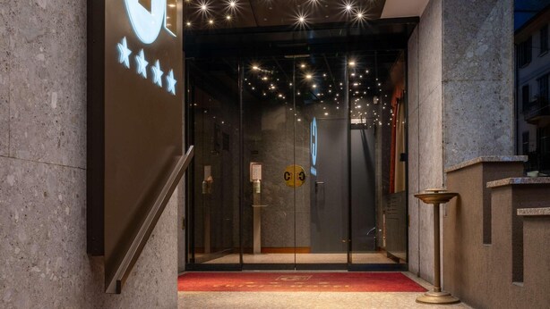 A hotel entrance with a red carpet, a staircase, and a modern ceiling design. - Hotel Crivi's (Milan)