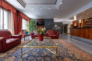 A lobby with a red leather sofa, a glass coffee table, and a patterned carpet. - Hotel Crivi's (Milan)