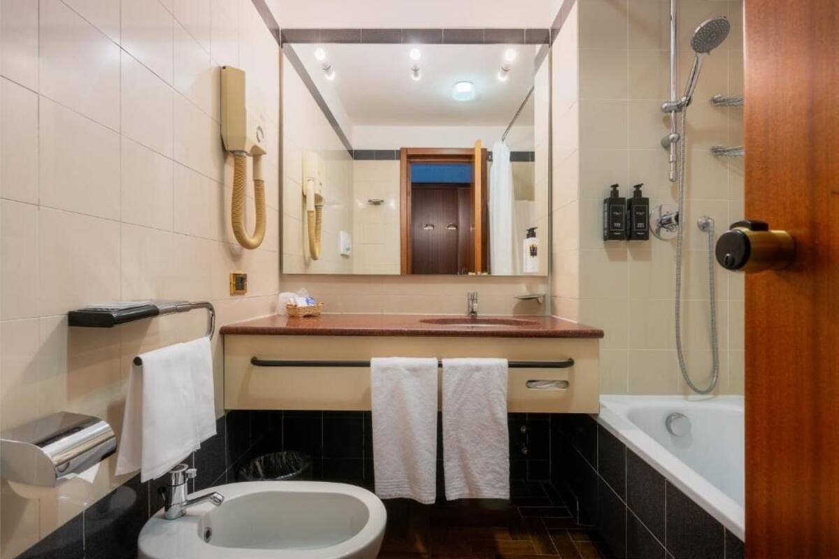 A modern bathroom with a sink, mirror, towel rack, shower, and toilet.