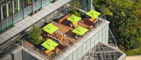 A rooftop terrace with outdoor seating and a glass-walled building.