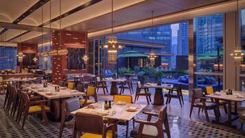 Un restaurant moderne doté d’une salle à manger, de grandes fenêtres et offrant une vue sur le paysage urbain.