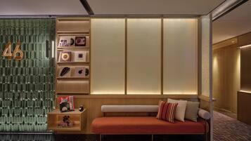 Una habitación con pared verde, un sofá, una mesita y una estantería con objetos.
