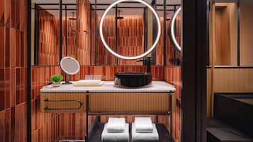 A modern bathroom with a vanity, mirror, towel rack, and a small plant.