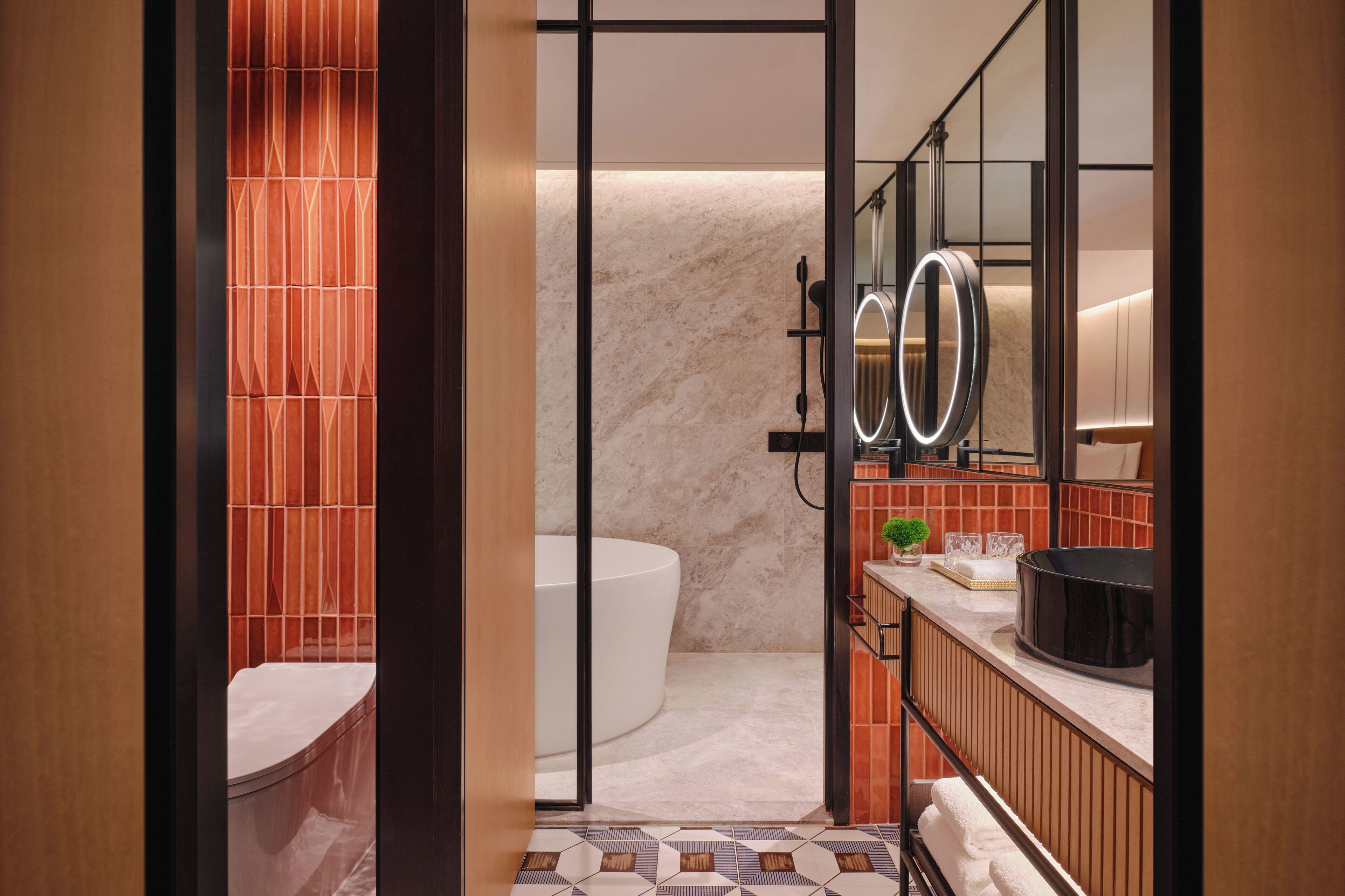 A modern bathroom with a bathtub, a large mirror, and a vanity with a sink and countertop.
