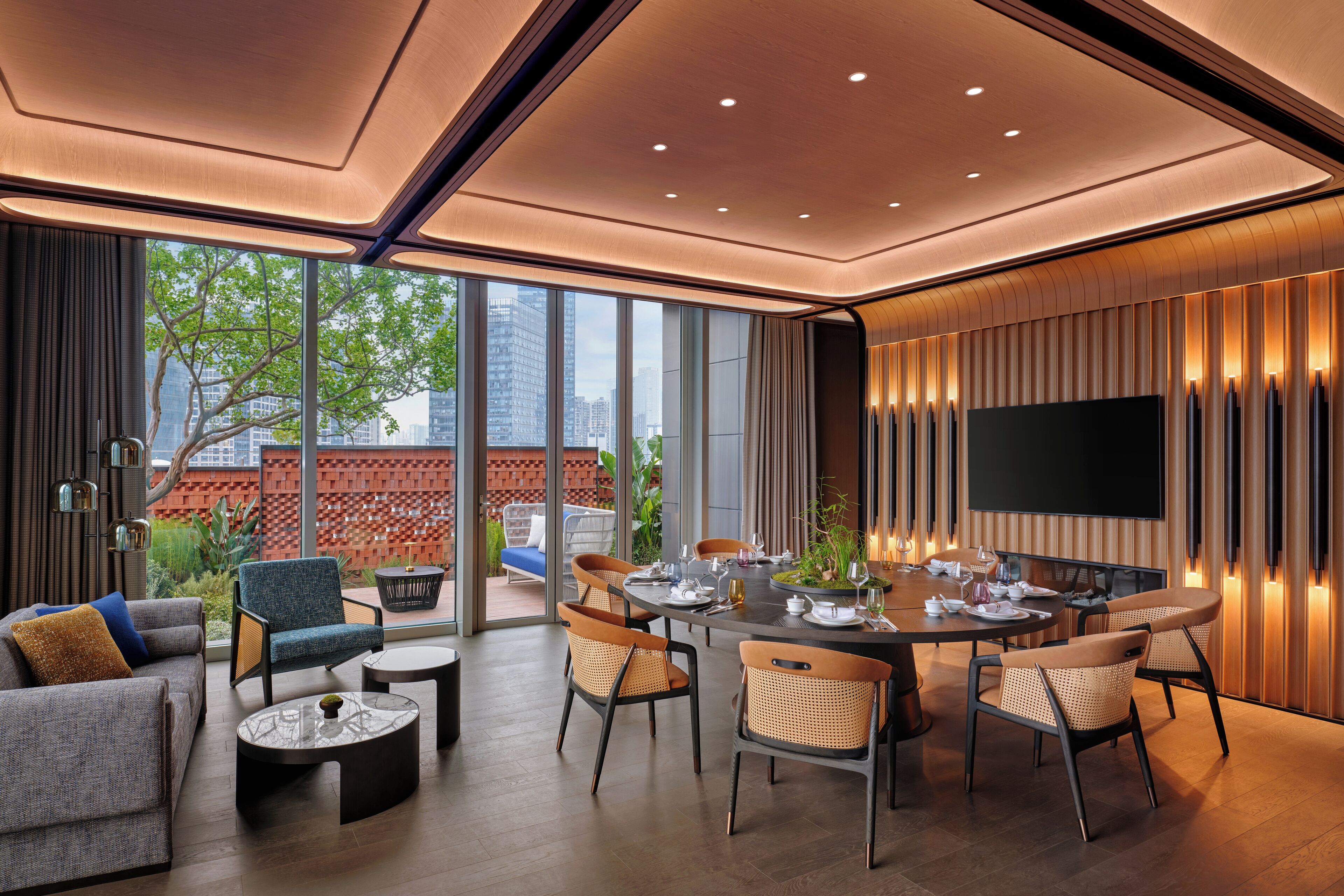 A modern dining area with a round table, chairs, and a flat-screen TV mounted on the wall.