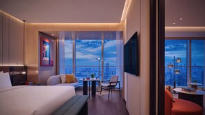 A modern hotel room with a large bed, a seating area with a table, and a view of the cityscape through large windows. - Hyatt Centric The Ring Chengdu (Chengdu)