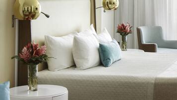 A hotel room with a bed, two bedside tables, a chair, and a large mirror with two spherical lights.