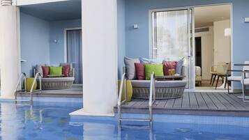A pool area with two seating areas, each with a set of colorful cushions and a small table.