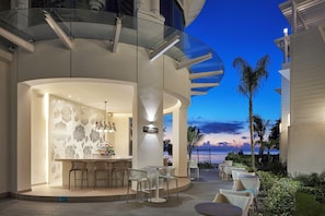 A modern bar area with a curved glass railing, a bar counter, and seating. - Azul Beach Resort Negril By Karisma (Negril)