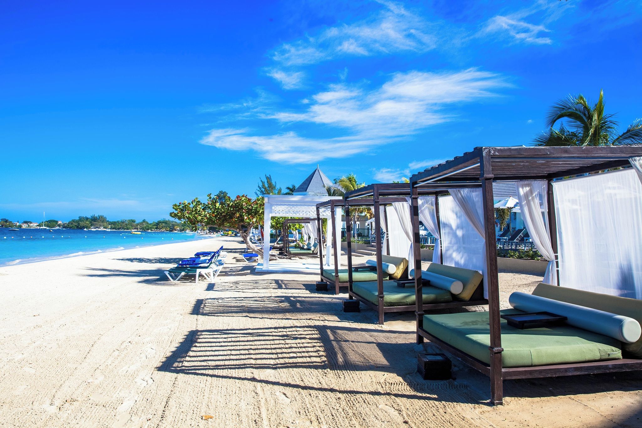 A beachside resort with overwater bungalows, clear blue skies, and a sandy beach.