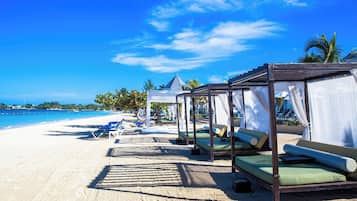 A beachside resort with overwater bungalows, clear blue skies, and a sandy beach.