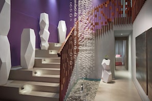 A modern staircase with geometric white steps and a wooden railing, leading to a room with a purple wall and a decorative bubble wall. - Azul Beach Resort Negril By Karisma (Negril)