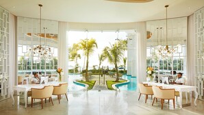 Un vaste espace intérieur avec vue sur la piscine, comprenant deux postes de travail équipés d’ordinateurs, des meubles blancs et un design moderne au niveau du plafond.