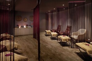 Un cuarto de spa con piso de madera, un mostrador de recepción y varias sillas de masaje.