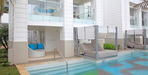 A pool area with two lounge chairs and a built-in seating area with cushions.
