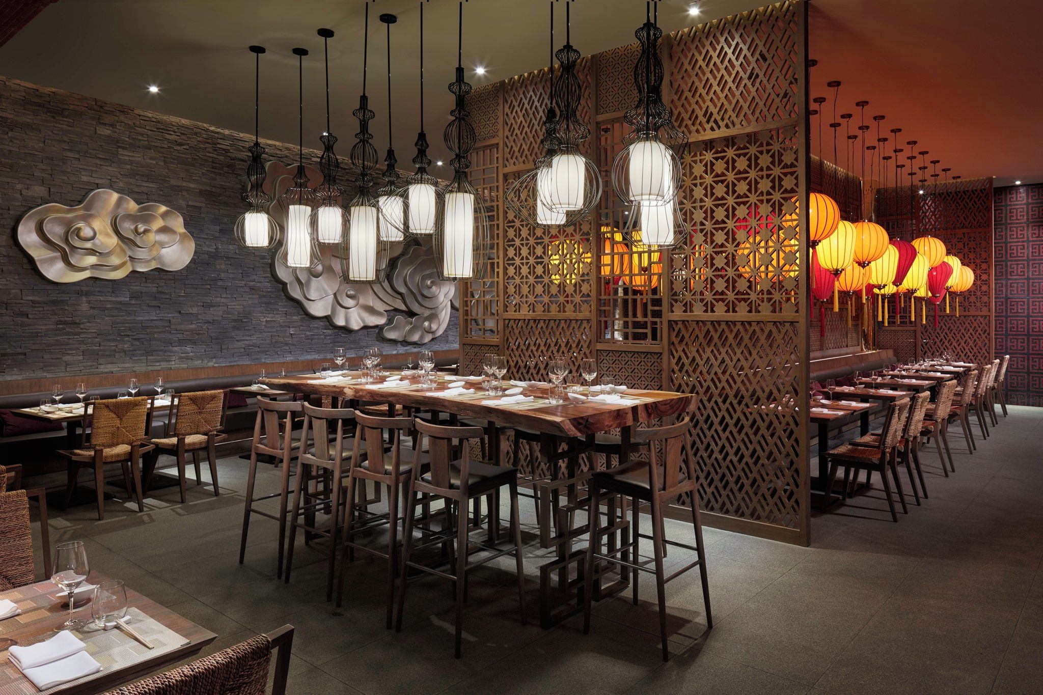 A restaurant with wooden tables and chairs, decorative wall art, and hanging lanterns.