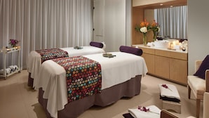 Une chambre d’hôtel avec deux lits, un coin salon, une coiffeuse avec un miroir et une petite table avec des articles de toilette.