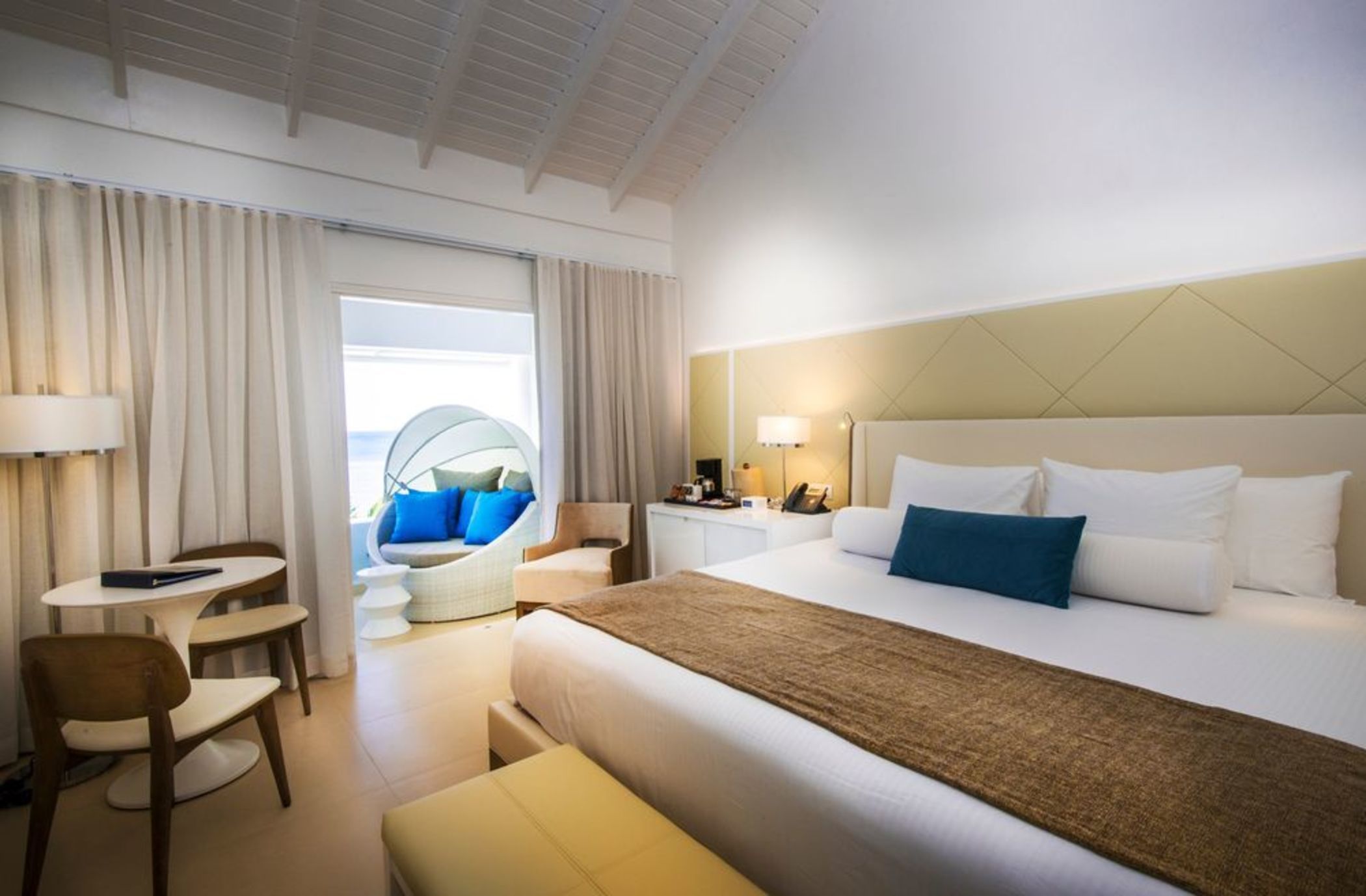 A hotel room with a bed, a desk, a chair, a sofa, and a view of the outside.