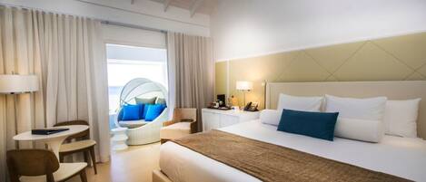A hotel room with a bed, a desk, a chair, a sofa, and a view of the outside.