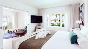 A modern hotel room with a large bed, a flat-screen TV, a seating area with a sofa and chairs, and a view of the outdoors. - Azul Beach Resort Negril By Karisma (Negril)