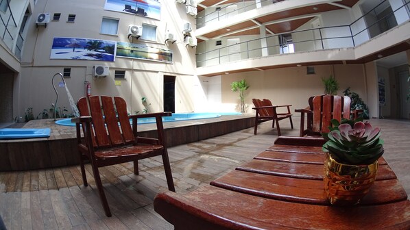 A multi-level outdoor area with wooden furniture, a pool, and potted plants.