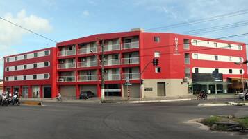 A multi-story hotel with a red facade, multiple balconies, and a ground-level entrance.