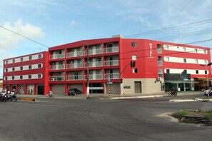 Un hôtel à plusieurs étages, doté d’une façade rouge, de nombreux balcons et d’une entrée au niveau du sol.