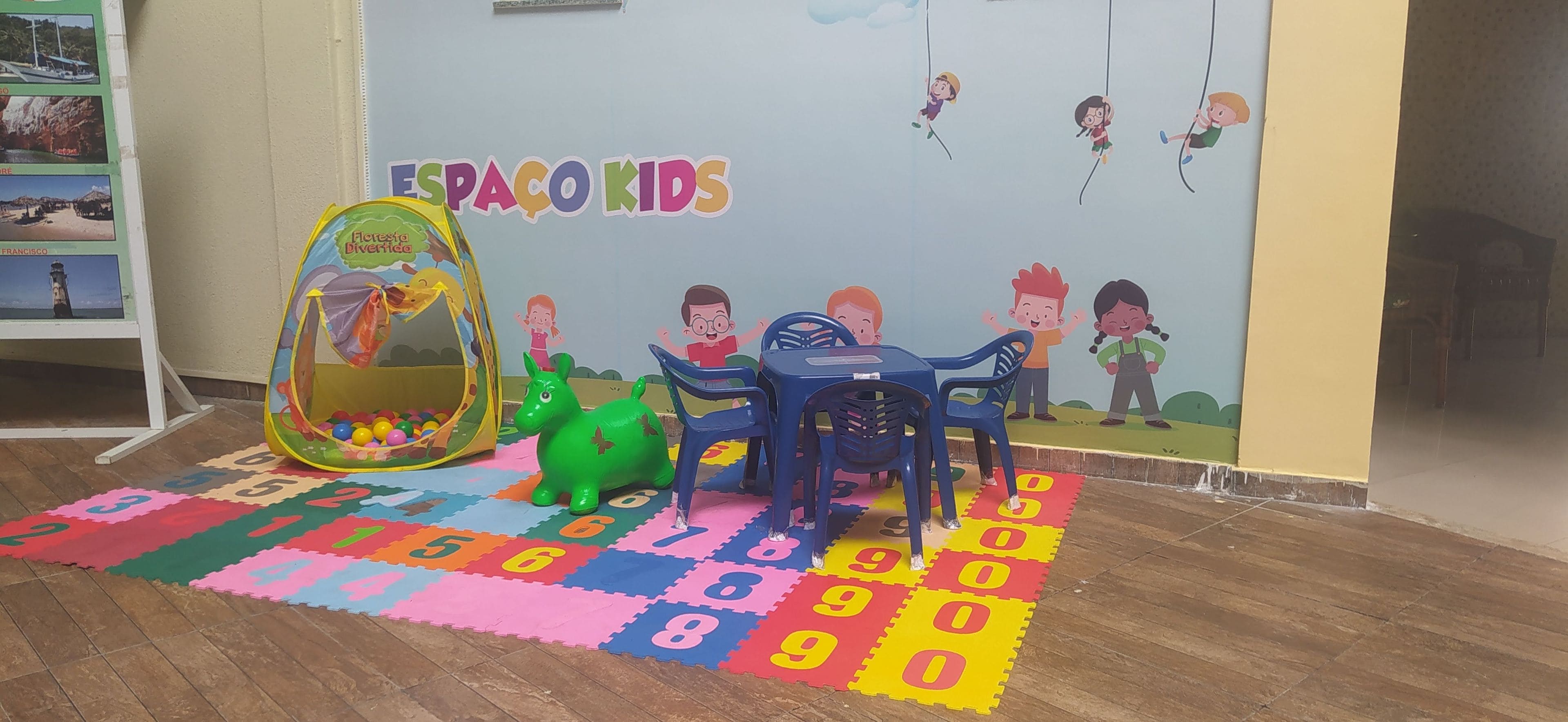 A children's play area with a colorful mat, a ball pit, and a dinosaur toy.