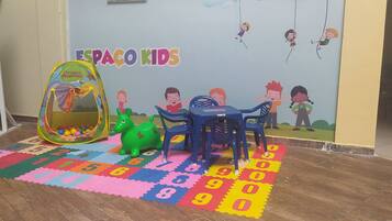 A children's play area with a colorful mat, a ball pit, and a dinosaur toy.