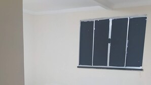 Una habitación con dos camas, una ventana con persianas, suelo de baldosas y una mesita.