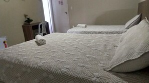A hotel room with two beds, each with a white quilted bedspread and pillows. There is a small table with a plant and a rolled towel on it. - Hotel Aracaju Express (Aracaju)