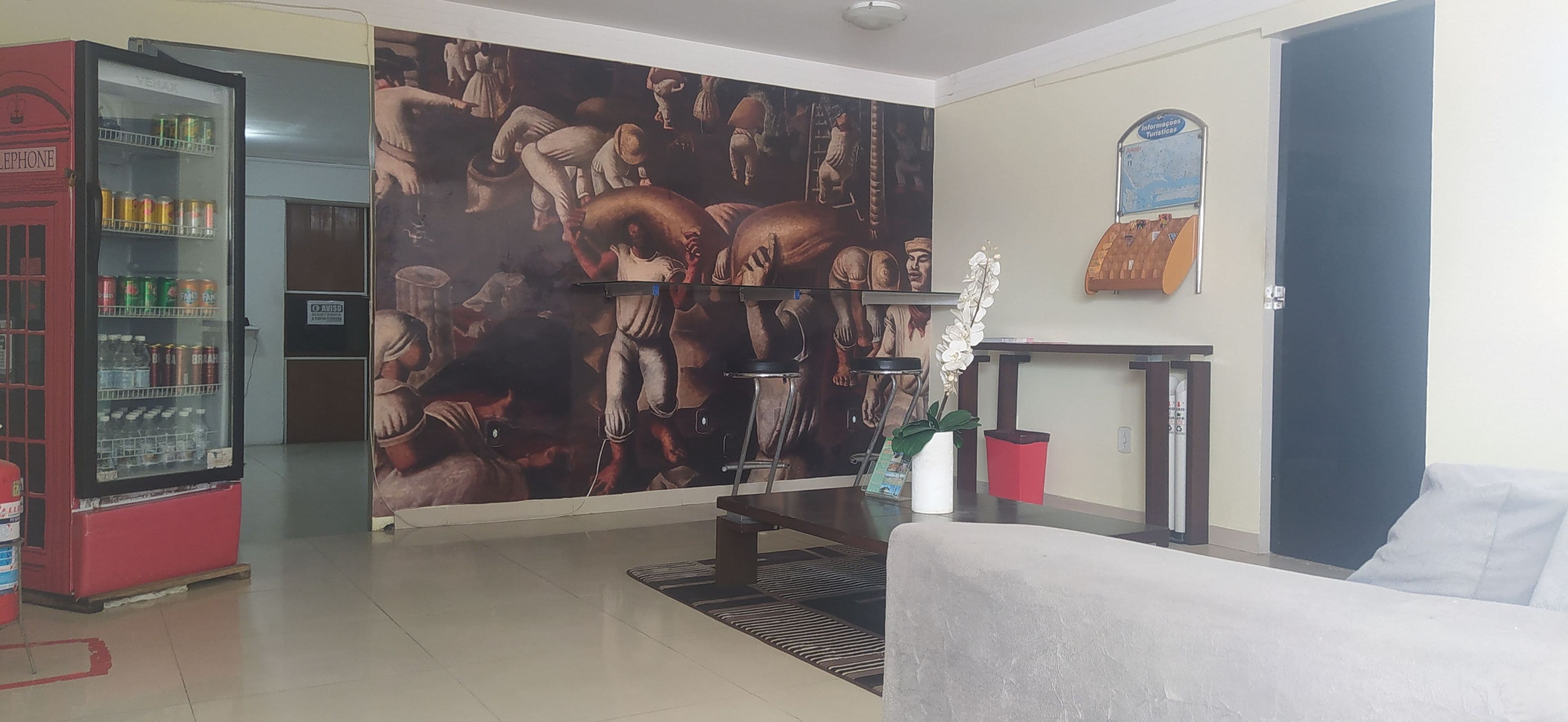 A living room with a red vending machine, a white sofa, a mural, and a small table with a potted plant.