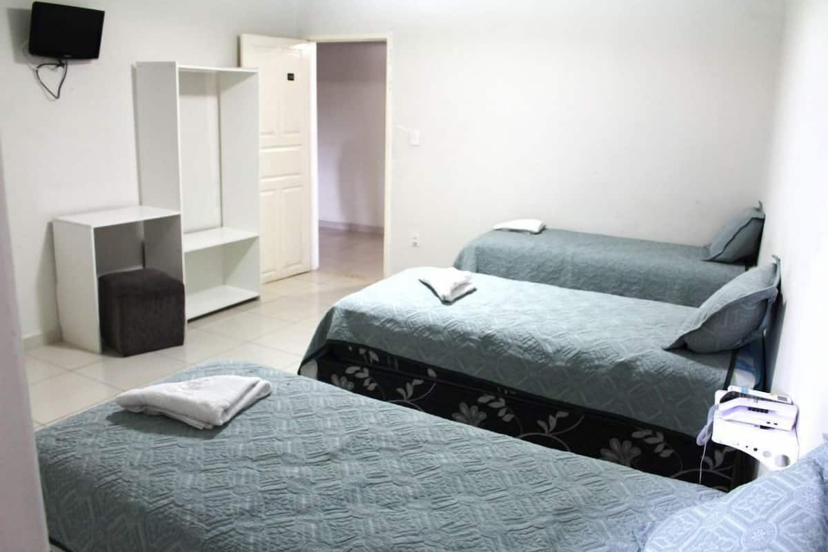 A room with two beds, a TV mounted on the wall, and a wardrobe.