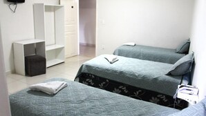Una habitación con dos camas, un televisor en la pared y un armario.