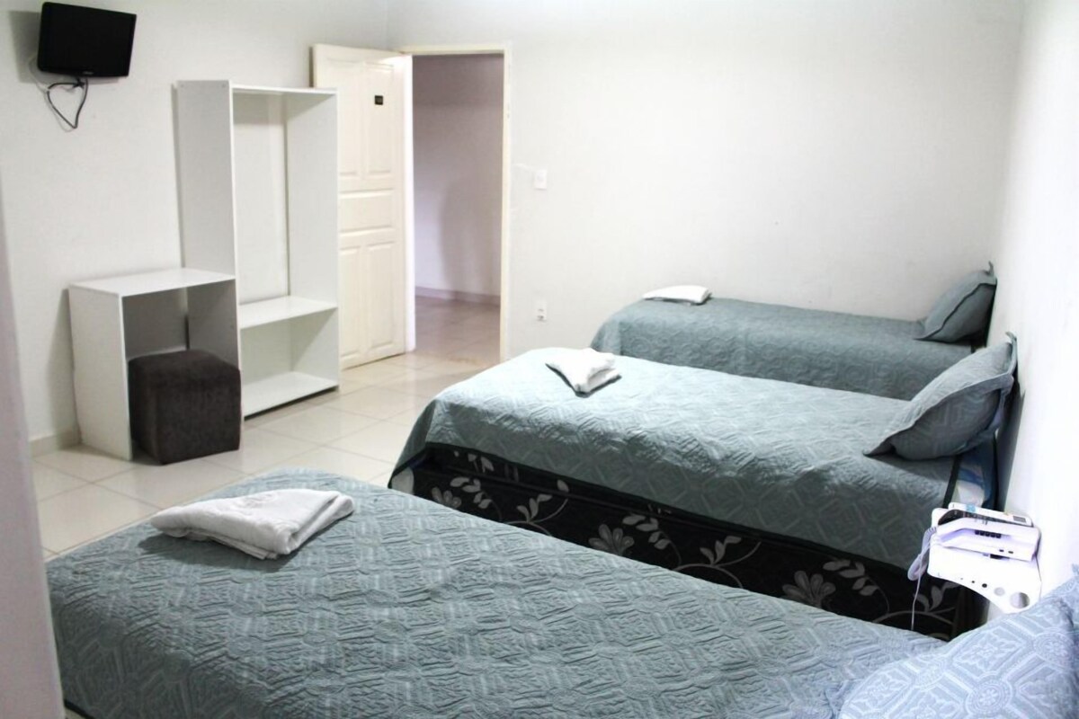 A room with two beds, a TV mounted on the wall, and a wardrobe.