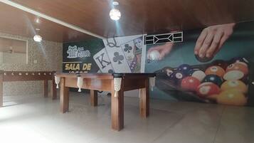 A billiards room with a pool table, two wooden benches, and a mural of a hand playing pool.
