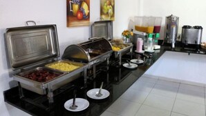 Montaje tipo buffet con distintas estaciones de comida, incluyendo una presentación de frutas y una estación de bebidas.